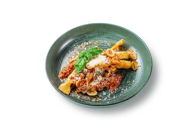 Pasta italiana Conchiglioni Rigati rellena de tomates secos y carne con albahaca y queso en un plato sobre un fondo blanco aislado