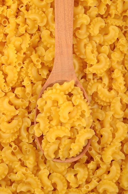 Pasta italiana cruda en una cuchara de madera