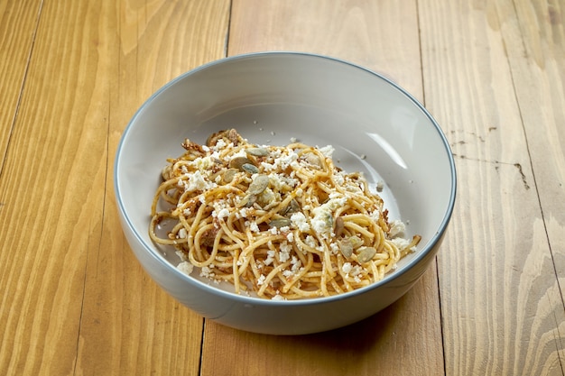 Pasta italiana (espagueti) con pesto, queso feta y pipas de calabaza. Plato vegetariano