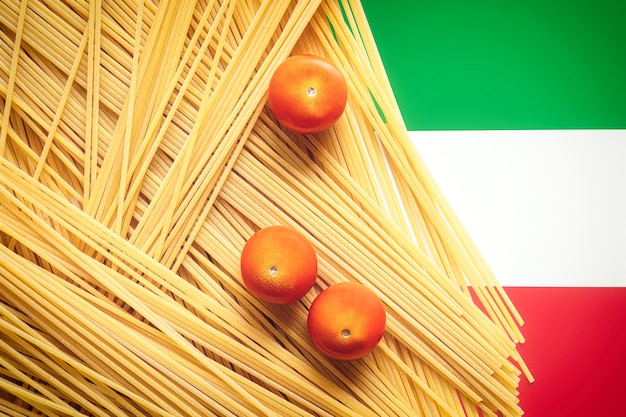 Pasta italiana de espaguetis crudos sin cocer, con tomates con bandera italiana en la mesa. Concepto de menú y comida italiana