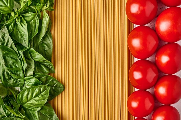 Pasta italiana de espaguetis con hojas de albahaca y tomates dispuestos en los colores de la bandera italiana