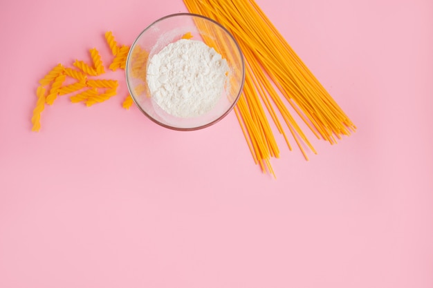 Pasta italiana. Espaguetis largos y pastas amarillos sobre fondo rosa.