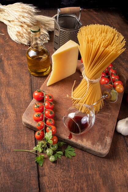 Pasta italiana (macarrones), una copa de vino, tomates, aceite de oliva, queso y especias