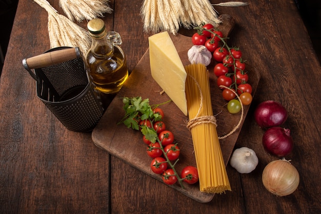Pasta italiana (macarrones), tomates, aceite de oliva, queso y especias sobre madera rústica