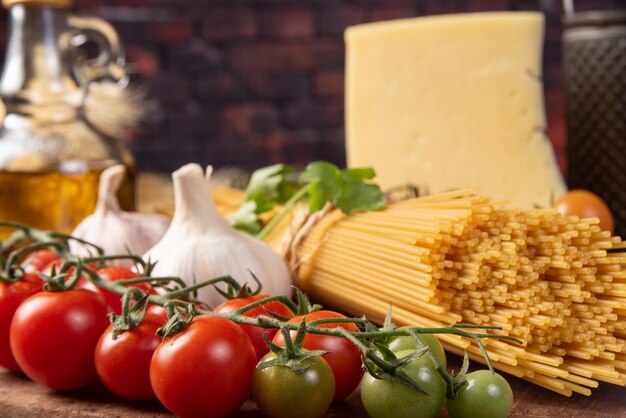 Foto pasta italiana (macarrones), tomates, aceite de oliva, queso y especias sobre madera rústica