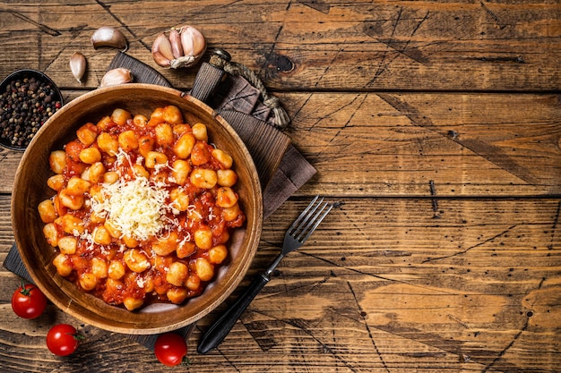 Pasta italiana de patata con ñoquis en salsa de tomate. Fondo de madera. Vista superior. Copie el espacio.