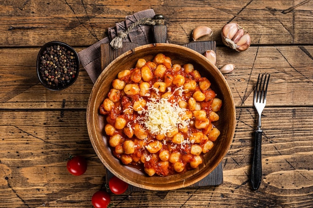 Pasta italiana de patatas con ñoquis en salsa de tomate. Fondo de madera. Vista superior.