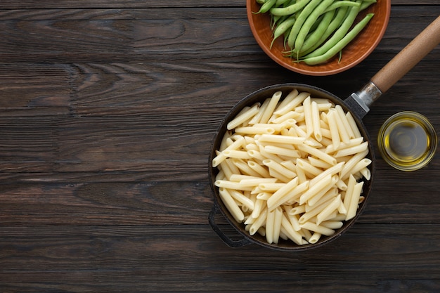 Pasta italiana penne en una sartén, estilo rústico.