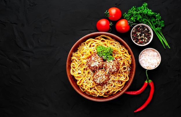 Pasta italiana con salsa de tomate y albóndigas en un plato con especias en piedra