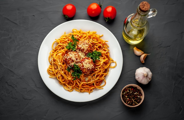 Pasta italiana con salsa de tomate y albóndigas en un plato con especias en piedra