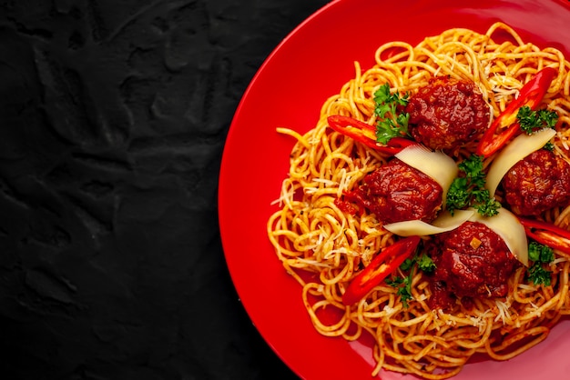 Pasta italiana con salsa de tomate y albóndigas en un plato con especias en piedra