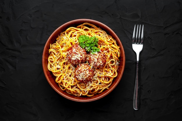 Pasta italiana con salsa de tomate y albóndigas en un plato sobre un fondo de piedra