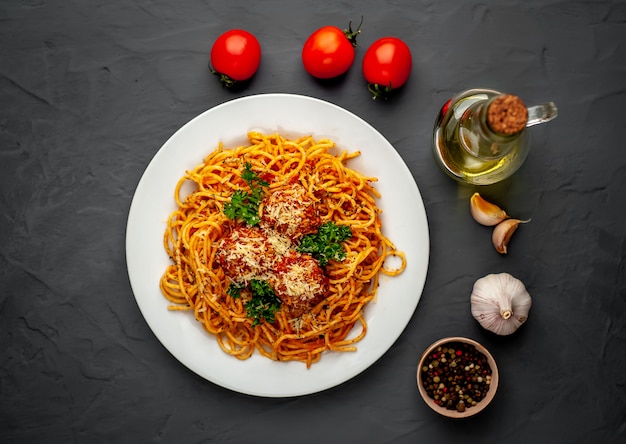 Pasta italiana con salsa de tomate y albóndigas en un plato sobre un fondo de piedra