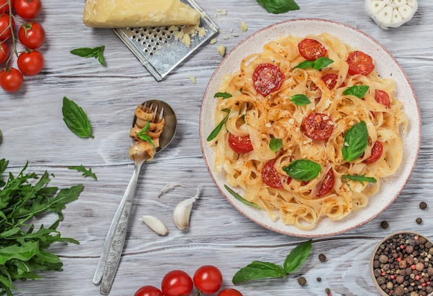 Foto pasta italiana con salsa, tomates cherry, albahaca y queso parmesano. delicioso plato de pasta
