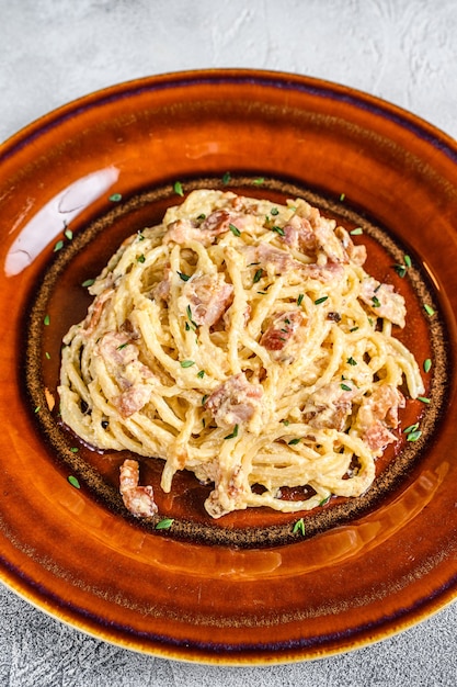 Pasta italiana Spaghetti Carbonara con tocino, queso parmesano duro y salsa de crema.