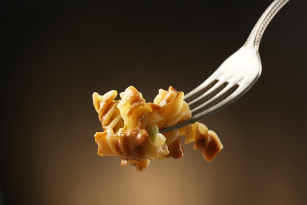 Pasta italiana en tenedor sobre fondo marrón oscuro