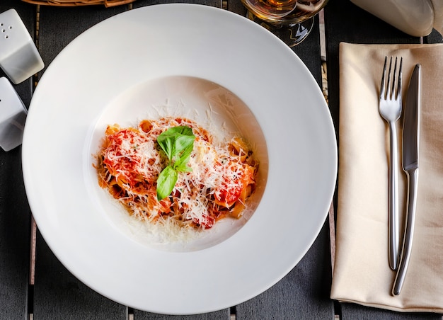 Pasta italiana con tomate, queso y una ramita de albahaca.