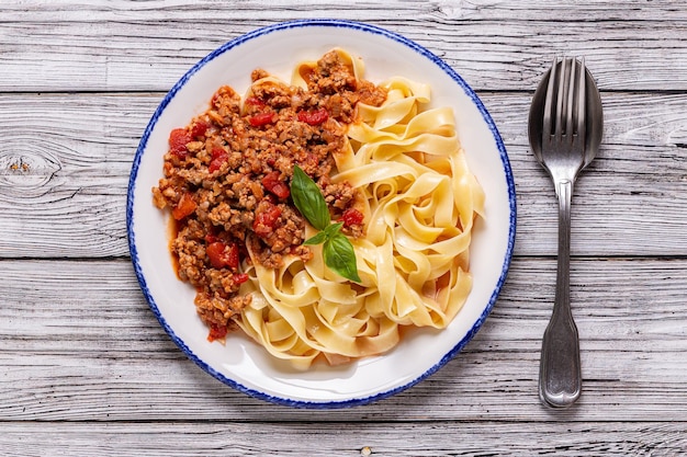 Pasta italiana tradicional bolognese em um prato branco sobre um fundo de madeira