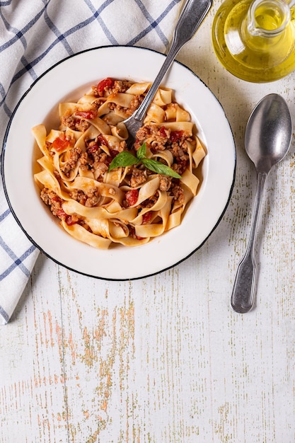 Pasta italiana tradicional bolognese em um prato branco sobre um fundo de madeira