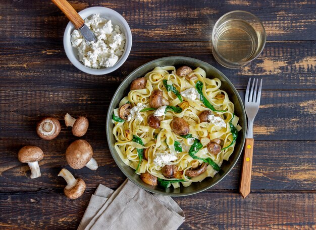 Pasta linguini con champiñones, queso blanco, espinacas y ajo. Alimentación saludable. Comida vegetariana. Dieta.