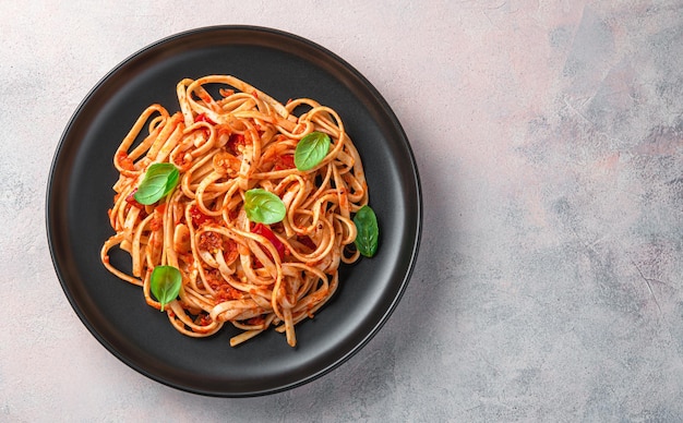 Pasta linguini italiana con salsa de tomate y albahaca fresca sobre un fondo claro