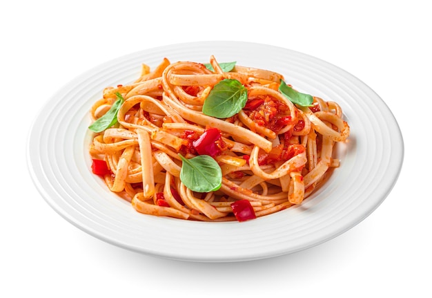 La pasta linguini tradicional italiana con tomate, pimienta y albahaca está aislada en un fondo blanco