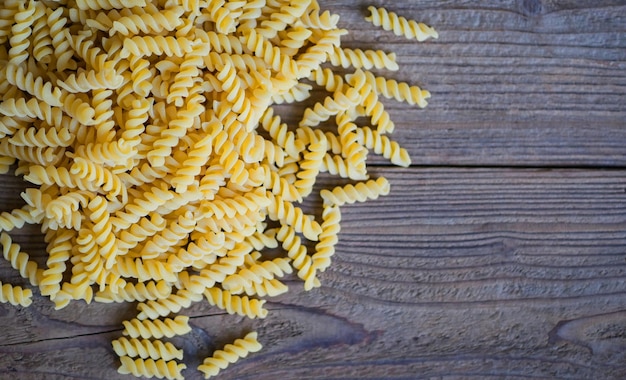 Pasta macarrones crudos sobre fondo de madera cerrar macarrones crudos pasta espiral sin cocer deliciosa pasta fusilli para cocinar comida vista superior