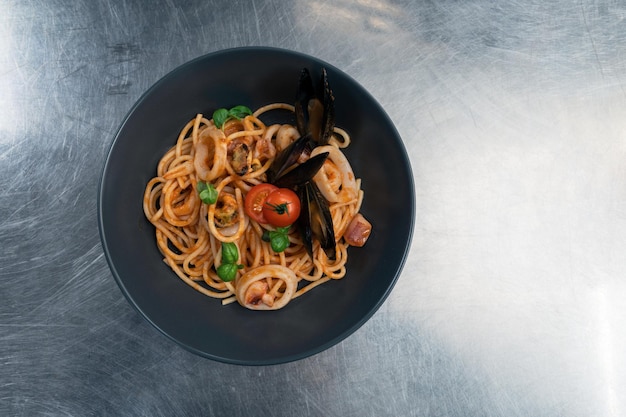 Pasta de marisco con mejillones con albahaca y tomate en plato negro