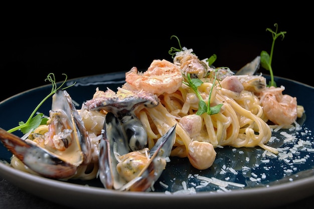 Pasta con marisco en un plato sobre un fondo oscuro