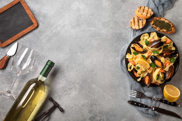 Pasta con marisco y vino blanco sobre mesa de piedra. Mejillones y gambas. Vista superior.