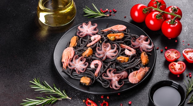 Pasta de mariscos negros con camarones, pulpo y mejillones. Comida gourmet mediterránea. Pasta negra con pulpo sobre una placa de piedra negra