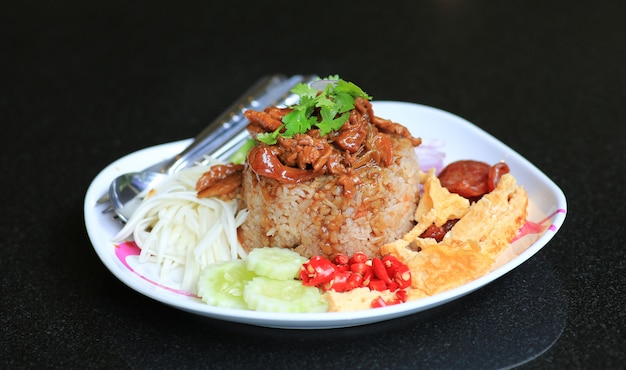 Pasta misturada do camarão do arroz fritado com carne de porco e ovo frito na placa na tabela preta.
