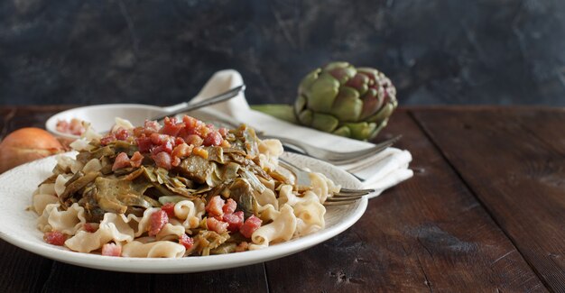 Pasta mit Artischocken und Speck mit Zutaten auf Holz