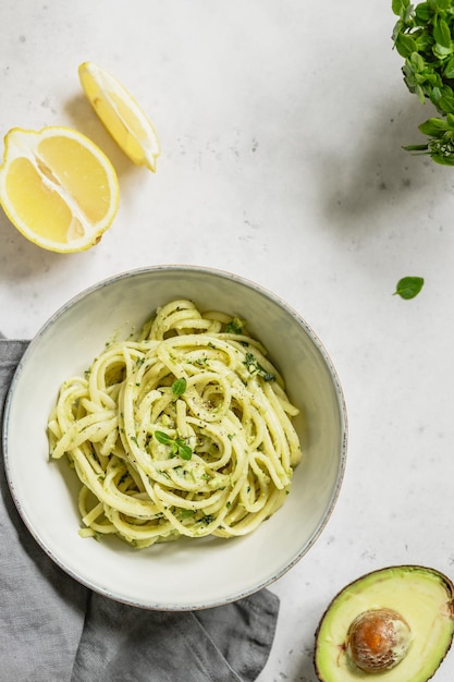 Pasta mit Avocado und griechischer Basilikum-Sauce in einer Keramikschale auf einem weißen Tisch Draufsicht des Kopierbereichs