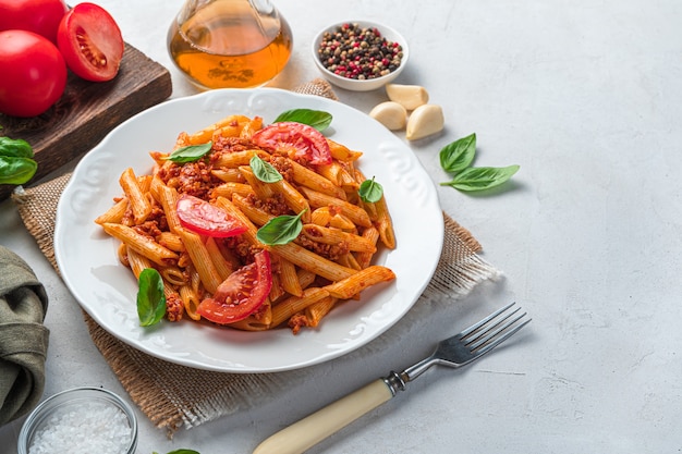 Pasta mit Bolognese-Sauce in einem weißen Teller auf hellgrauem Hintergrund. Ein traditionelles italienisches Gericht.