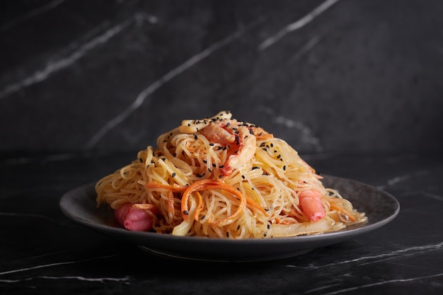 Pasta mit Garnelen und Meeresfrüchten, Spaghetti, Nudeln, Teller auf dunklem Hintergrund, asiatische Küche