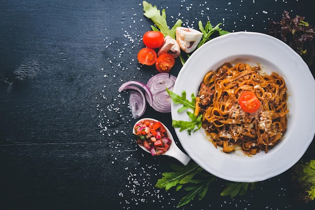 Pasta mit kirschtomaten oliven und pilzen mit parmesan-käse italienisches essen auf einer schwarzen holzoberfläche freier platz für ihren text ansicht von oben