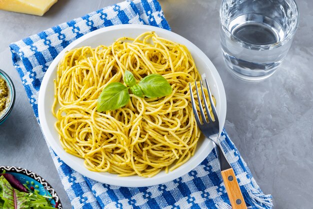 Pasta mit Sauce Pesto und Zutaten. Spaghetti mit Pesto-Sauce und Basilikum auf grauem Hintergrund. Traditionelle italienische Küche. Foodstyling