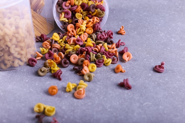 Pasta multicolor con la adición de colorante vegetal natural. Dispersos de una lata sobre una mesa de concreto