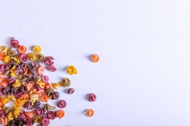 Pasta multicolor con la adición de colorante vegetal natural. Esparcidos sobre una mesa blanca