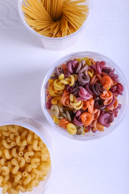 Pasta multicolor con la adición de colorante vegetal natural. En un frasco sobre una mesa blanca