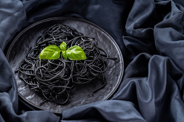 Pasta negra y albahaca sobre un fondo oscuro