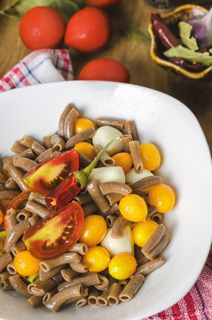 Pasta negra con tomate y queso mozzarella.