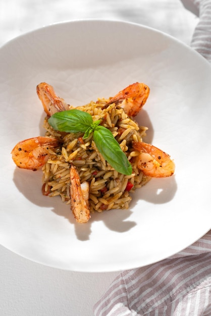 Pasta orzo con gambas sobre fondo blanco para el menú del restaurante