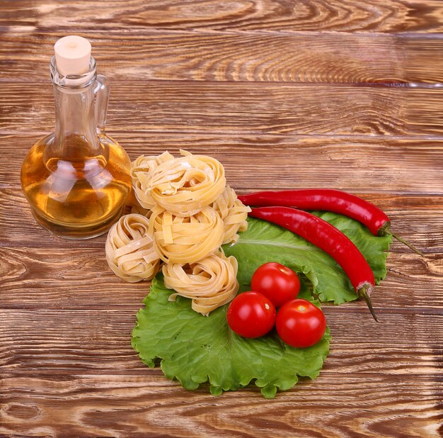 Pasta en la pared de madera con tomate, lechuga pimiento, aceite de oliva y pimiento