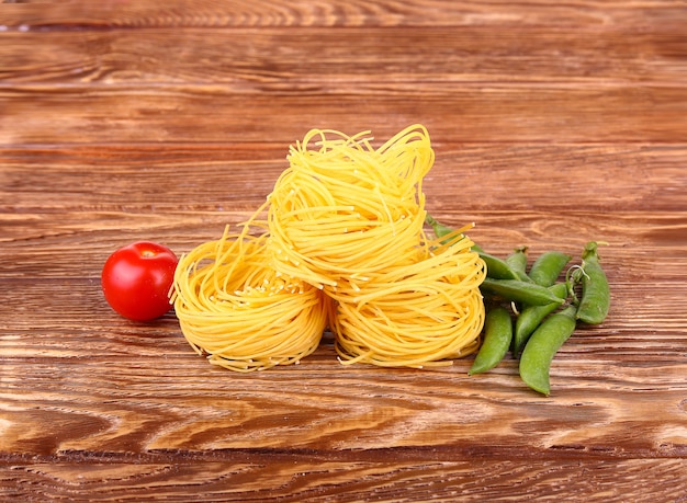 Foto pasta en la pared de madera con tomates y guisantes