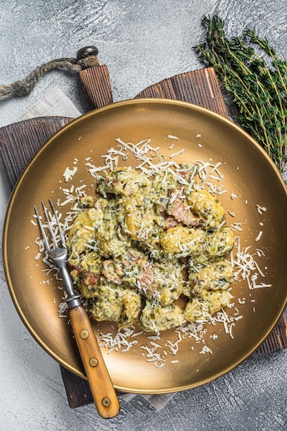 Pasta de patata Gnocchi cocida con espinacas y jamón de parma en un plato. Fondo blanco. Vista superior.