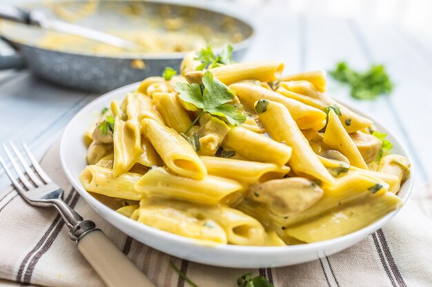 Pasta Pene mit Hähnchenstücken Champignons Parmesan-Käse-Sauce und Kräuterdekoration