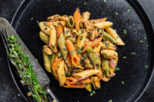 Pasta Penne de color italiano con mejillones en un plato. Vista superior.