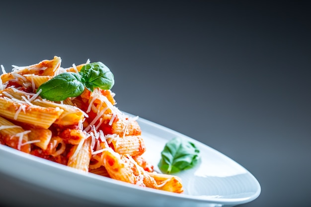 Pasta Penne mit Tomaten-Bolognese-Sauce, Parmesan und Basilikum. Mediterranes Essen. Italienische Küche.